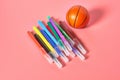 Heap of multi colored felt pens near toy basketball ball lies on pink desk in kindergarten Royalty Free Stock Photo