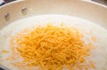 Heap of orange grated cheese in a pan of cream gravy.