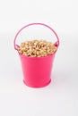 Heap pearl barley grains in pink bucket on white background