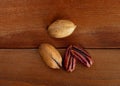 Heap of pecans in shell and decorticated peeled nut on wooden table