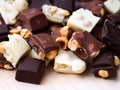 Heap of pieces of milk chocolate, white chocolate and dark chocolate with hazelnuts