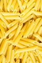Heap Pile of Uncooked Italian Penne Pasta. Bright Vibrant Yellow Color. Top View. Food Background Pattern. Royalty Free Stock Photo