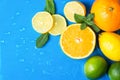 Heap of raw juicy citrus fruits oranges lemons lime fresh mint on wet blue background with water drops. Summer beverages Royalty Free Stock Photo