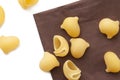 Heap of raw macaroni shells on brown napkin, selective focus.