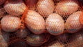 Heap of raw red potatoes in red string bag for sale at local city market Royalty Free Stock Photo