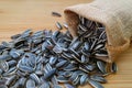 Raw sunflower seeds scattered from burlap bag on wooden table Royalty Free Stock Photo