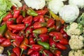 A heap of red bell peppers together with cauliflowers and white cabbages for sale at a local public market