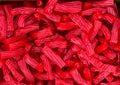 Heap of red strawberry licorice twizzlers red vine candies at supermarket. Creative sweet food confectionery pattern. Kids treats