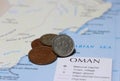 Heap of Rial Omani money coin put on the map. Concept of finance or travel