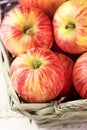 Heap of ripe organic red striped apples in a wicker basket. White plank wood garden or kitchen table.