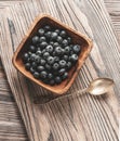 heap ripe sweet blueberries and spoon on wooden table top view