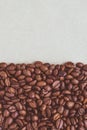 A heap of roasted coffee beans on a neutral paper background with copy space.