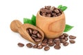 Heap of roasted coffee beans in wooden bowl and scoop with leaves isolated on white background with clipping path and Royalty Free Stock Photo