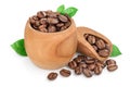 Heap of roasted coffee beans in wooden bowl and scoop with leaves isolated on white background with clipping path and Royalty Free Stock Photo