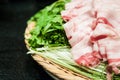 Heap of rolled pieces raw sliced bacon on green mizuna lettuce i