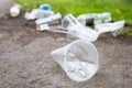 Heap of rubbish on the path, closeup. Empty used plastic cups and plastic bottles