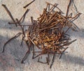 Heap of rusty curved nails are piled on granite stone