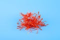 Heap of red saffron threads, on a blue background. Expensive spice