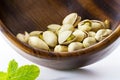 Heap salted pistachio nuts on wooden spoon