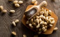 Heap of salted, roasted green pistachio nuts snack in wooden bowl on wood background with sea salt in wooden scoop, healthy food Royalty Free Stock Photo