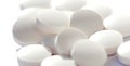 Heap of simple tiny round white pills loose, group of small tablets on white, macro, closeup, focus on one pill. New medicine