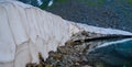 Heap of snow near a lake coast in mountain Royalty Free Stock Photo