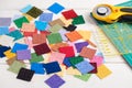 Heap square pieces of colorful fabrics on white wooden surface, quilting accessories