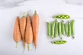 Heap of sweet carrots and peas in pods on the white kitchen table Royalty Free Stock Photo