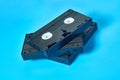 Heap of three black old vhs video cassettes lies on blue desk. Concept of 90s