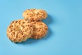 Heap of three fresh circle oat cookies with hole and peanuts lies on blue desk on kitchen