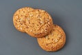 Heap of three fresh homemade cookies with seeds of sunflower and sesame lies on dark scratched concrete table on kitchen