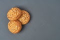 Heap of three fresh homemade cookies with seeds of sunflower and sesame lies on dark scratched concrete table on kitchen