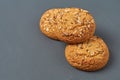 Heap of three fresh homemade cookies with seeds of sunflower and sesame lies on dark scratched concrete table on kitchen