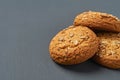 Heap of three fresh homemade cookies with seeds of sunflower and sesame lies on dark scratched concrete table on kitchen