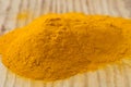 Heap of tumeric spice on wooden board