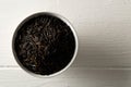 Heap of uncooked, raw, black wild rice grains in white bowl on white wooden table background, flat lay top view from above Royalty Free Stock Photo