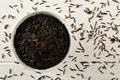 Heap of uncooked, raw, black wild rice grains in white bowl on white wooden table background, flat lay top view from above Royalty Free Stock Photo