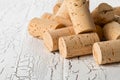 Heap of unused, new, brown natural wine corks on white wooden bo