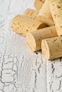 Heap of unused, new, brown natural wine corks on white wooden bo