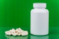 Heap of vitamins and white plastic bottle on green Royalty Free Stock Photo