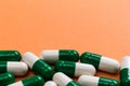 Heap of White and green capsules on orange background. Royalty Free Stock Photo