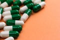 Heap of White and green capsules on orange background. Royalty Free Stock Photo