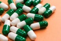 Heap of White and green capsules on orange background.