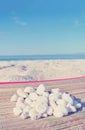 Heap of white pebbles on white sandy beach; faded, retro style