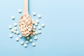 Heap of white pills on colored background. Tablets scattered on a table. Pile of red soft gelatin capsule. Vitamins and Royalty Free Stock Photo