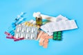 Heap of white pills and yellow capsules, bottle, syringes, bandage, patches and ampoules with red vaccine on blue background Royalty Free Stock Photo