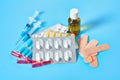 Heap of white pills and yellow capsules, bottle, syringes, patches and ampoules with red vaccine on blue background Royalty Free Stock Photo