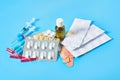 Heap of white pills and yellow capsules, bottle, syringes, patches and ampoules with red vaccine on blue background Royalty Free Stock Photo