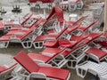 Heap of white plastic chaise lounge with red mattresses and sunshades on sea side cement beach top view Royalty Free Stock Photo