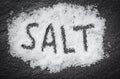 Heap white salt on dark background with text SALT Royalty Free Stock Photo